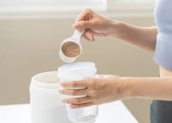 Женщина добавляет комплексный протеин в шейкер